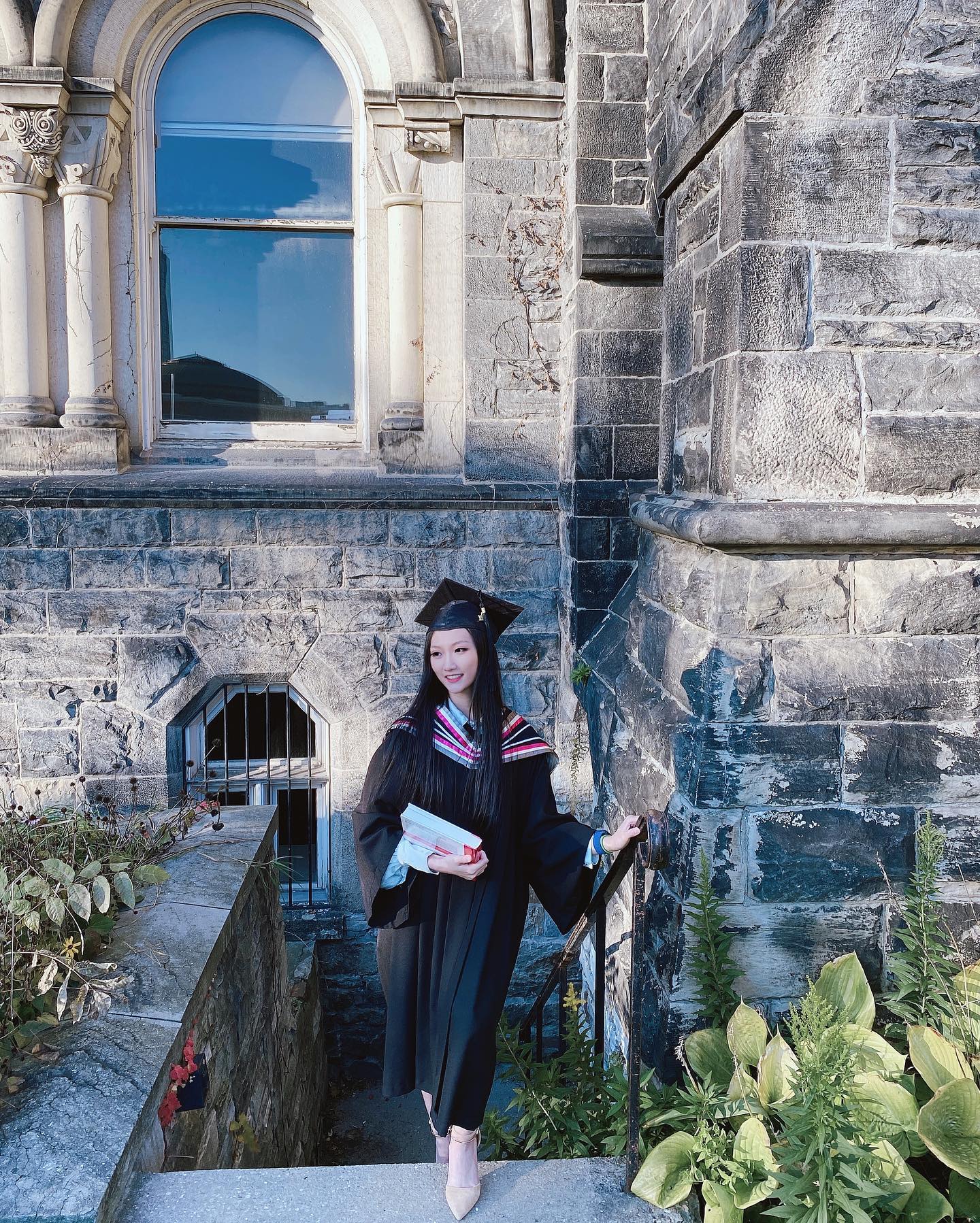 Iris at graduation in front of a university