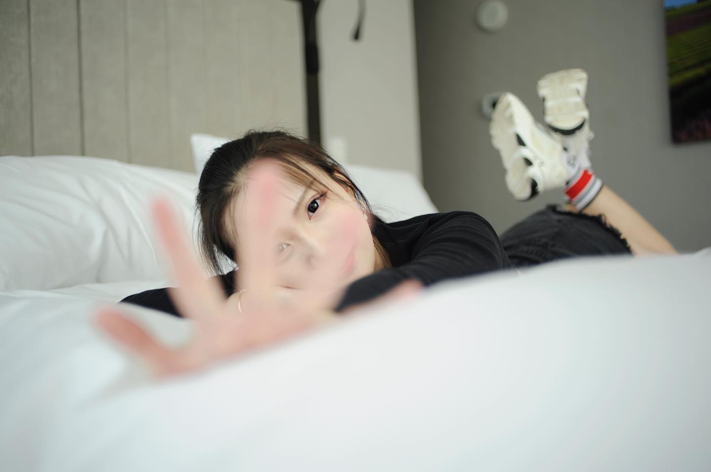 Iris lying on a bed, reaching toward the camera